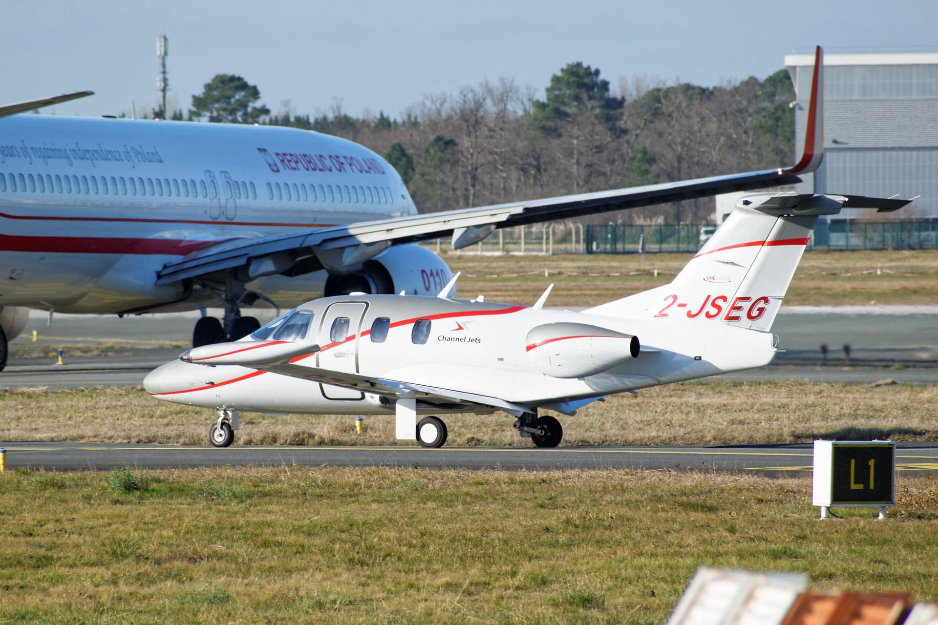 A white Eclipse 500 taxiing in front of a "Republic of Poland" jet.