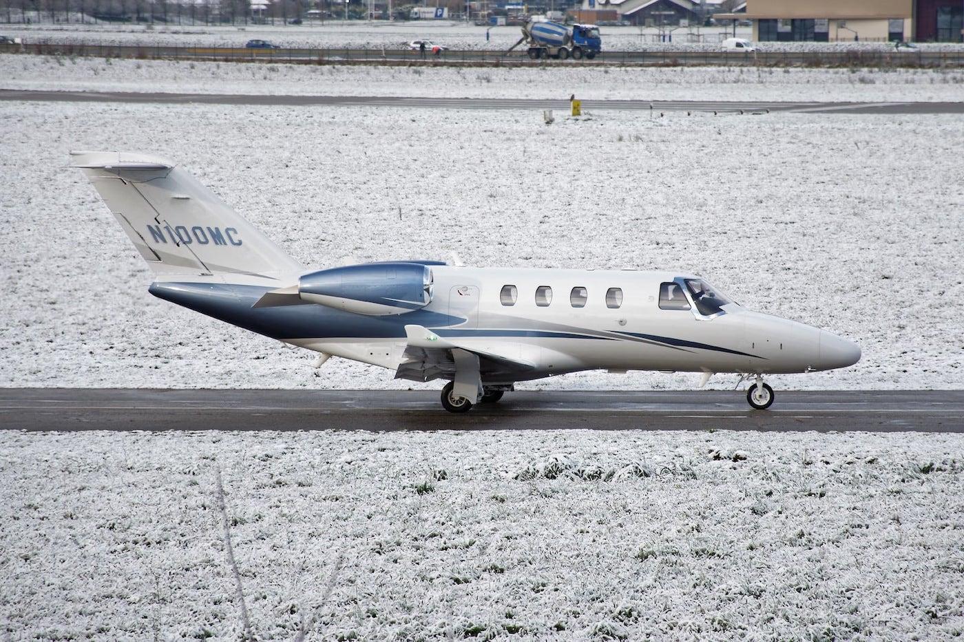 A Cessna Citation M2 taxiing at a snowy airport.