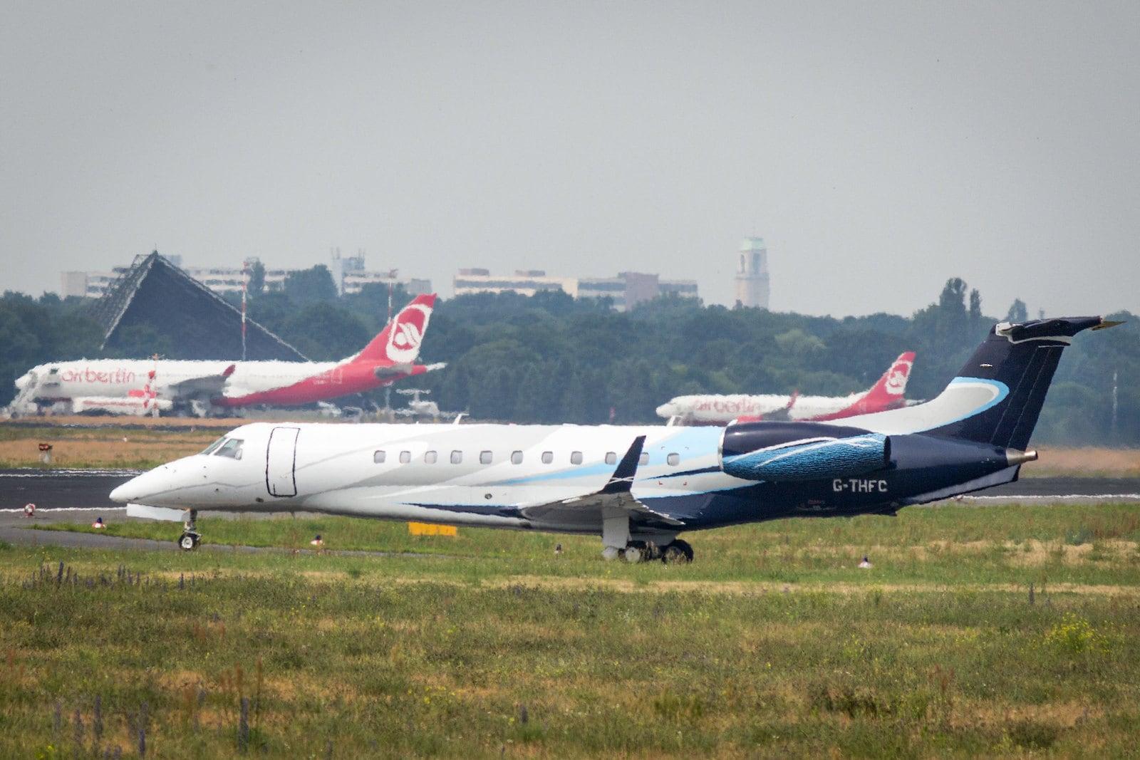 A private jet in front of two parked Air Berlin commercial airliners.