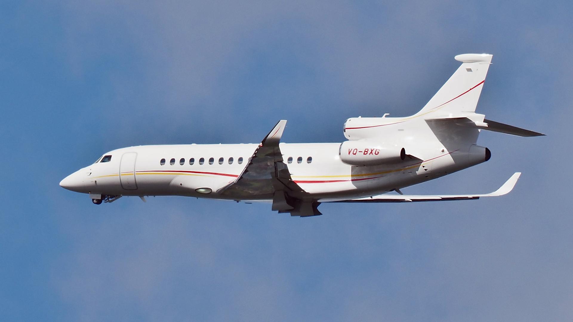 A white Dassault Falcon 8X with red and yellow accents sporting tail number VQ-BXG.