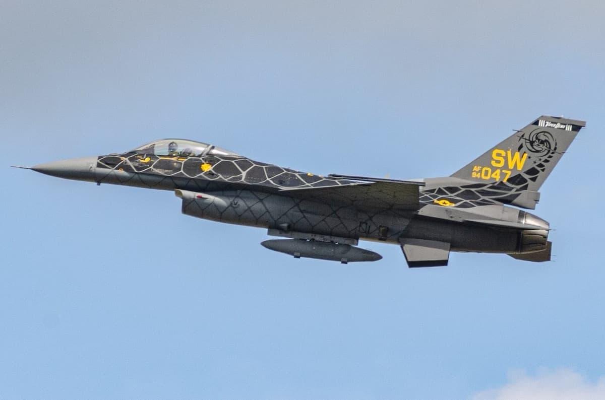 A USAF F-16 painted in the "Venom" livery which features black scales and yellow accents.