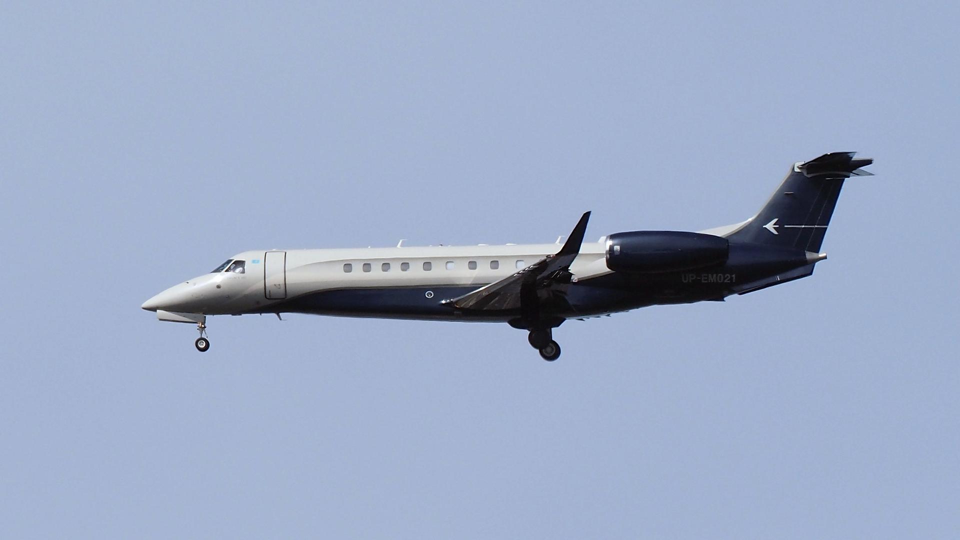 A grey and dark blue Embraer Legacy 650E with its gear down.