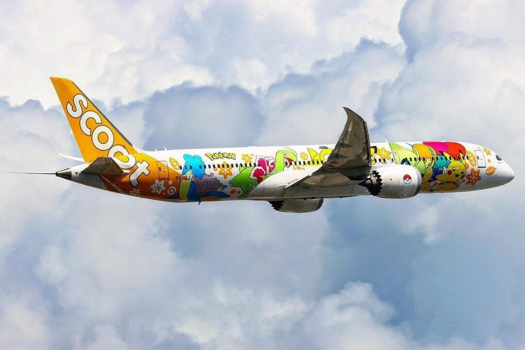 A Scoot 787 Dreamliner in the Pikachu livery flying into a cloudy backdrop.