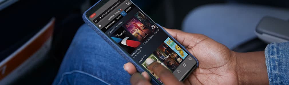 A hand holding a smartphone with a web browser opened, showing the American Airlines inflight WiFi interface.