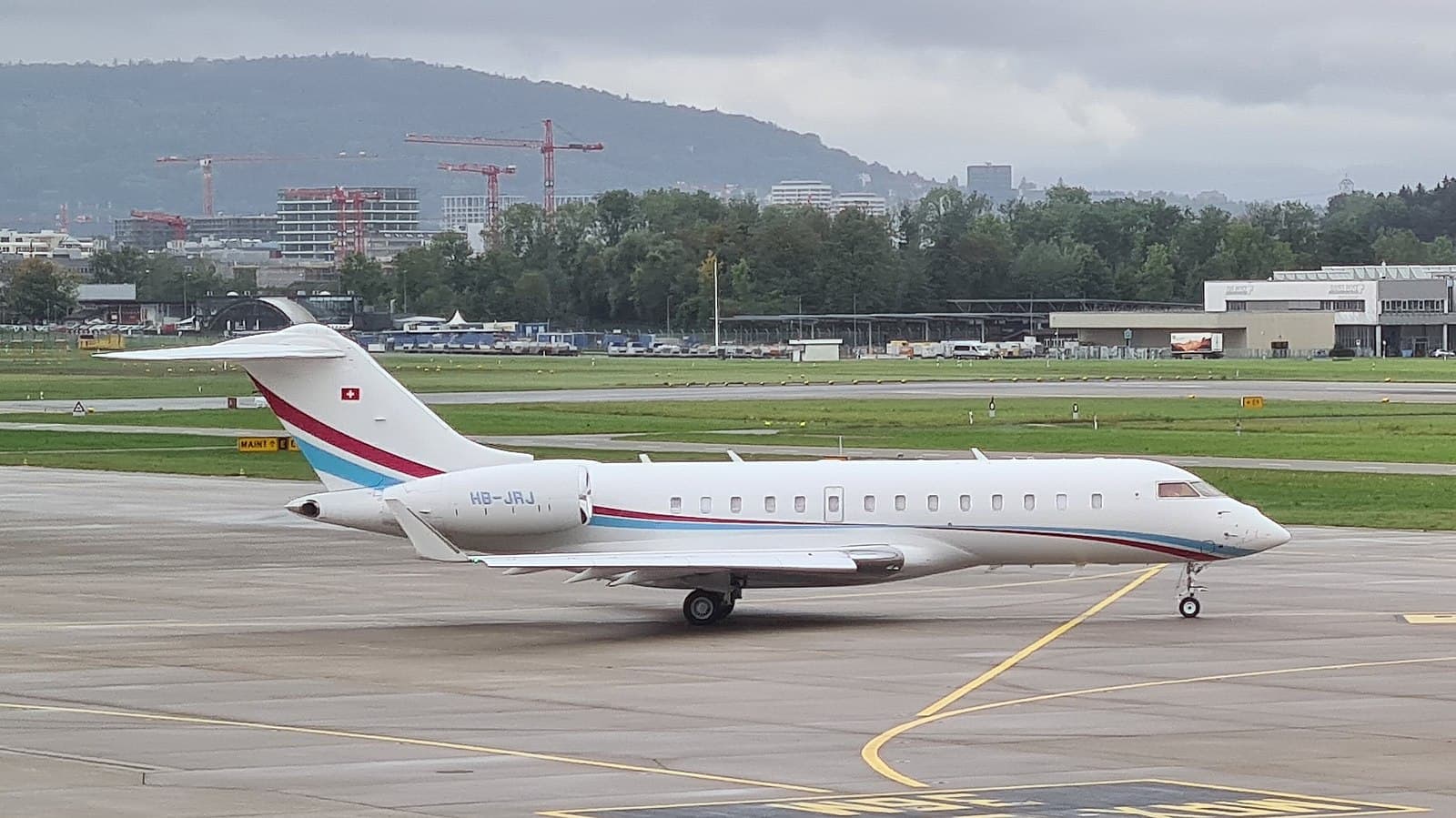 A Bombardier Global 5500 with blue and red accent stripes taxiing on the tarmac.